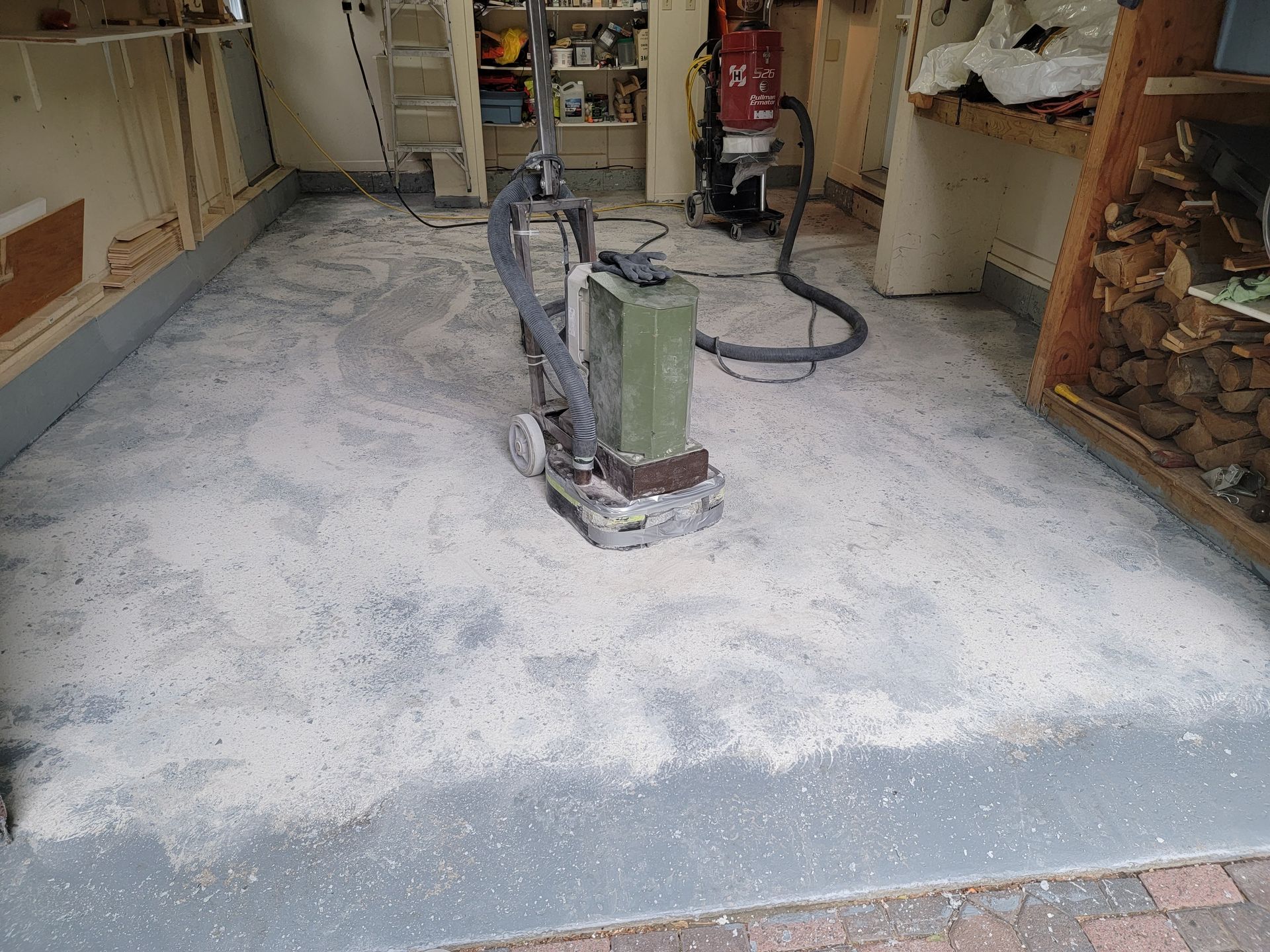 Ponceuse à plancher en action, ponçage d'une pièce ; la sciure recouvre le plancher.