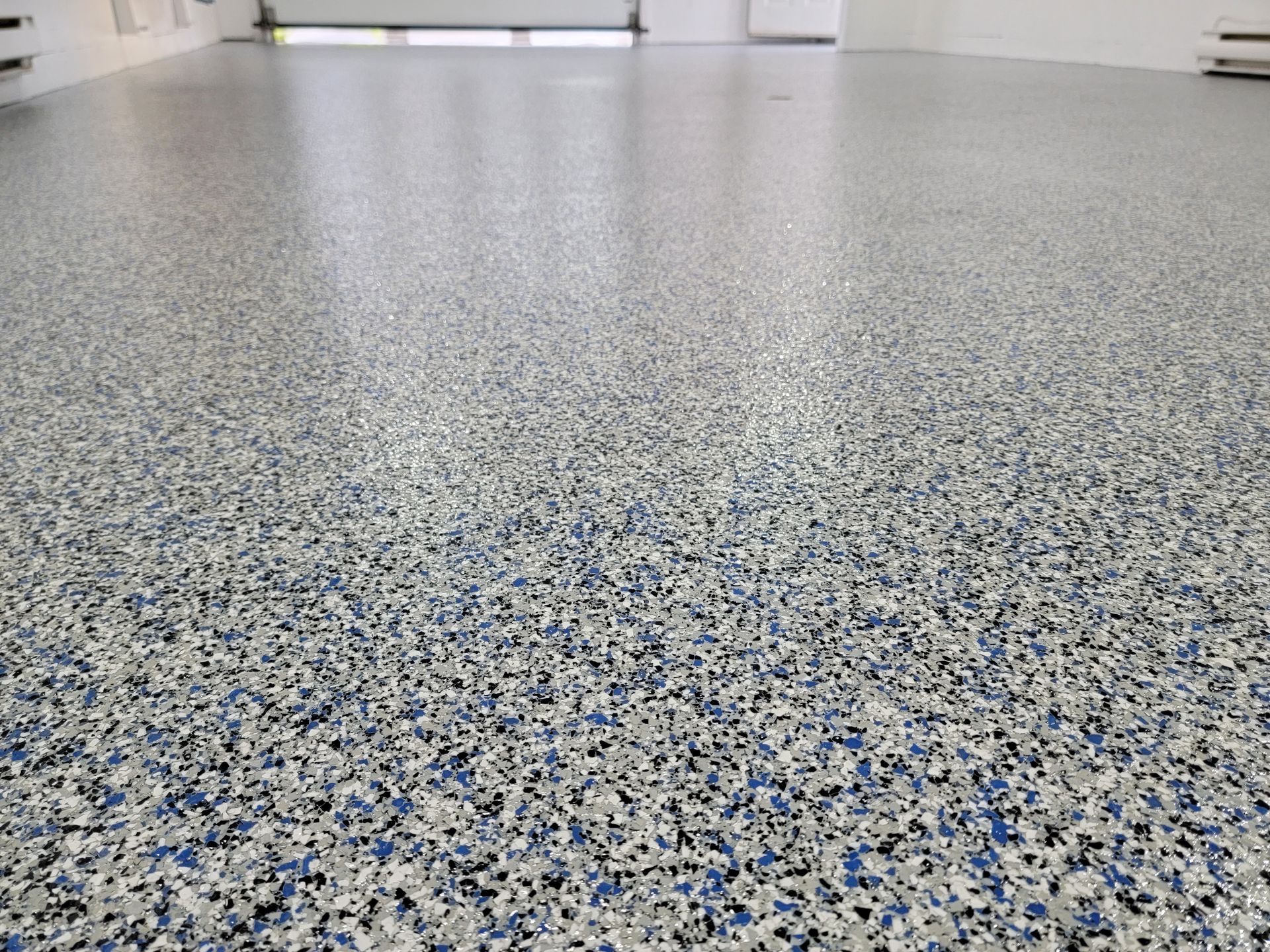 Plancher de garage recouvert d'époxy, moucheté d'éclats bleus, gris et noirs.