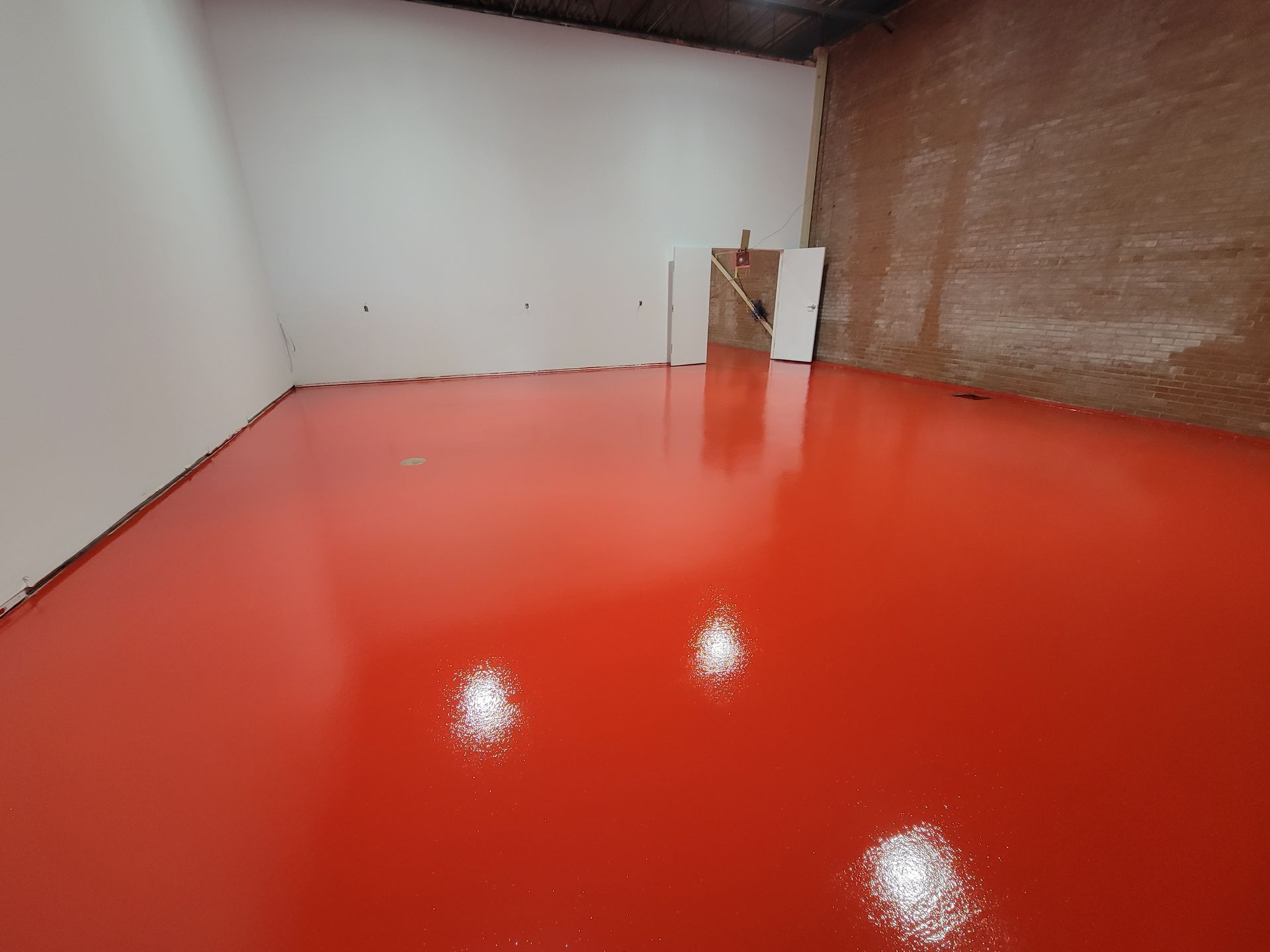 Sol époxy rouge dans une pièce vide avec des murs blancs et marron.