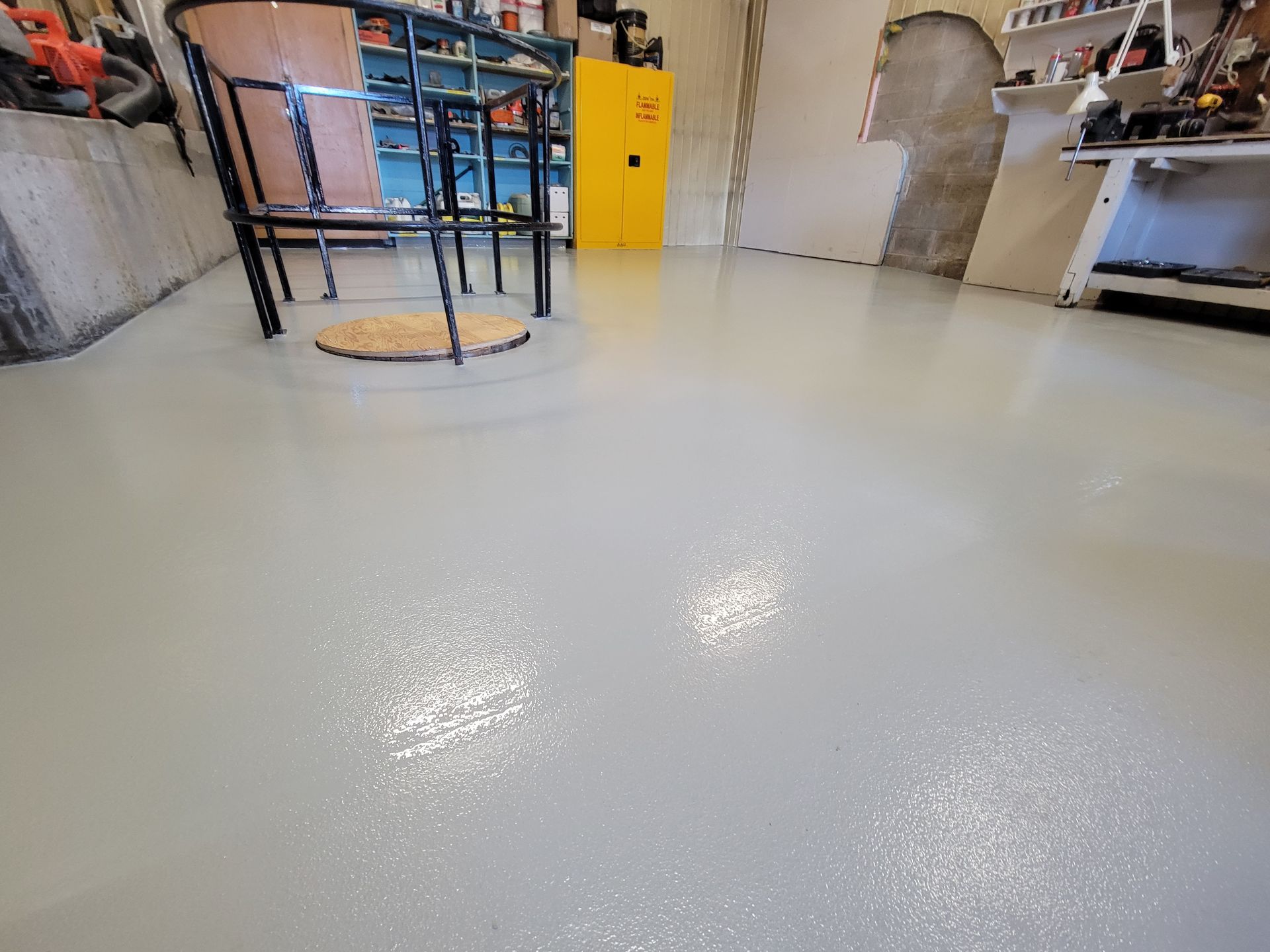Sol époxy gris clair dans un garage. Chaise et étagères en arrière-plan.