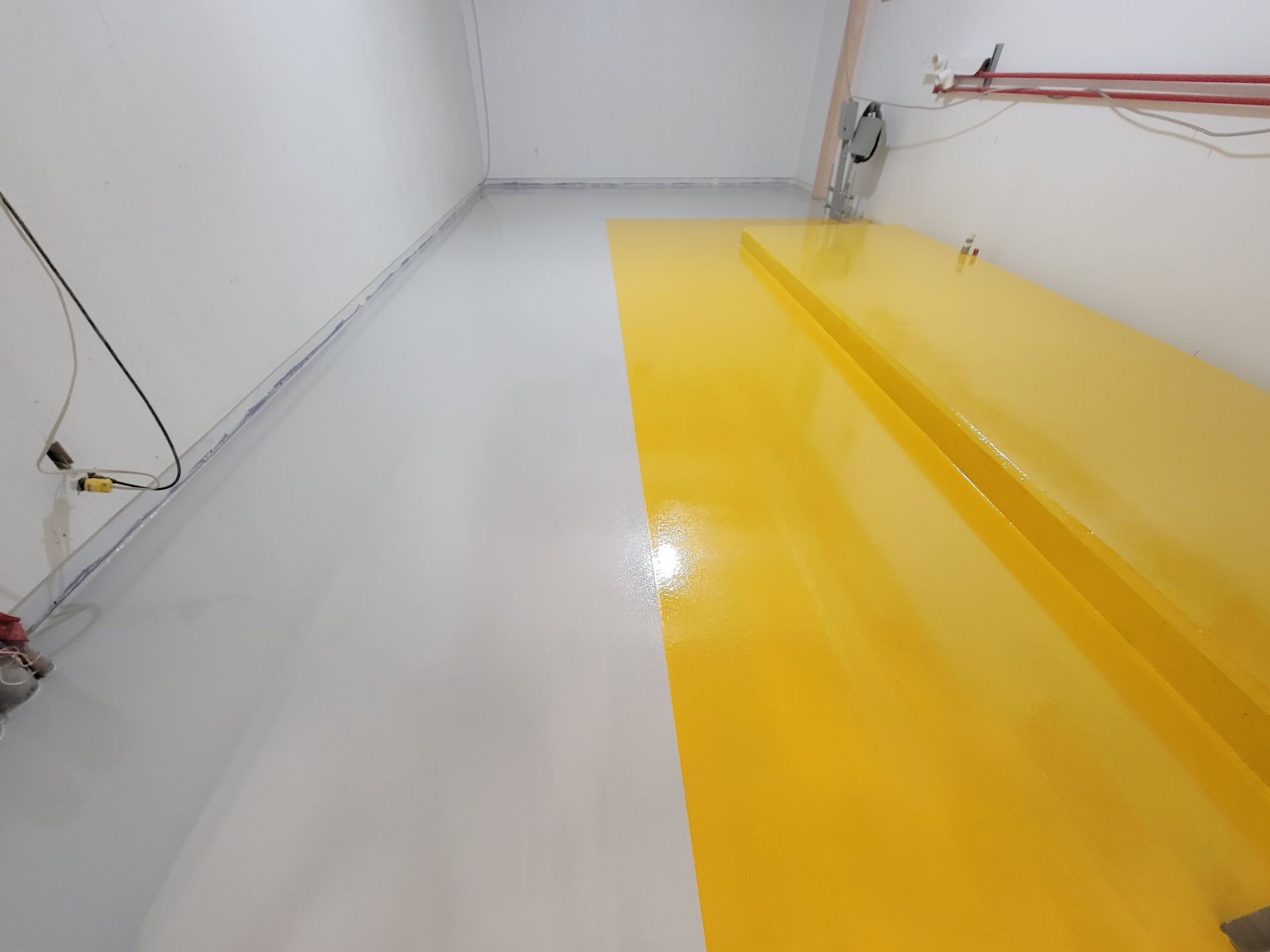 Une pièce au sol gris et jaune, avec des murs blancs.