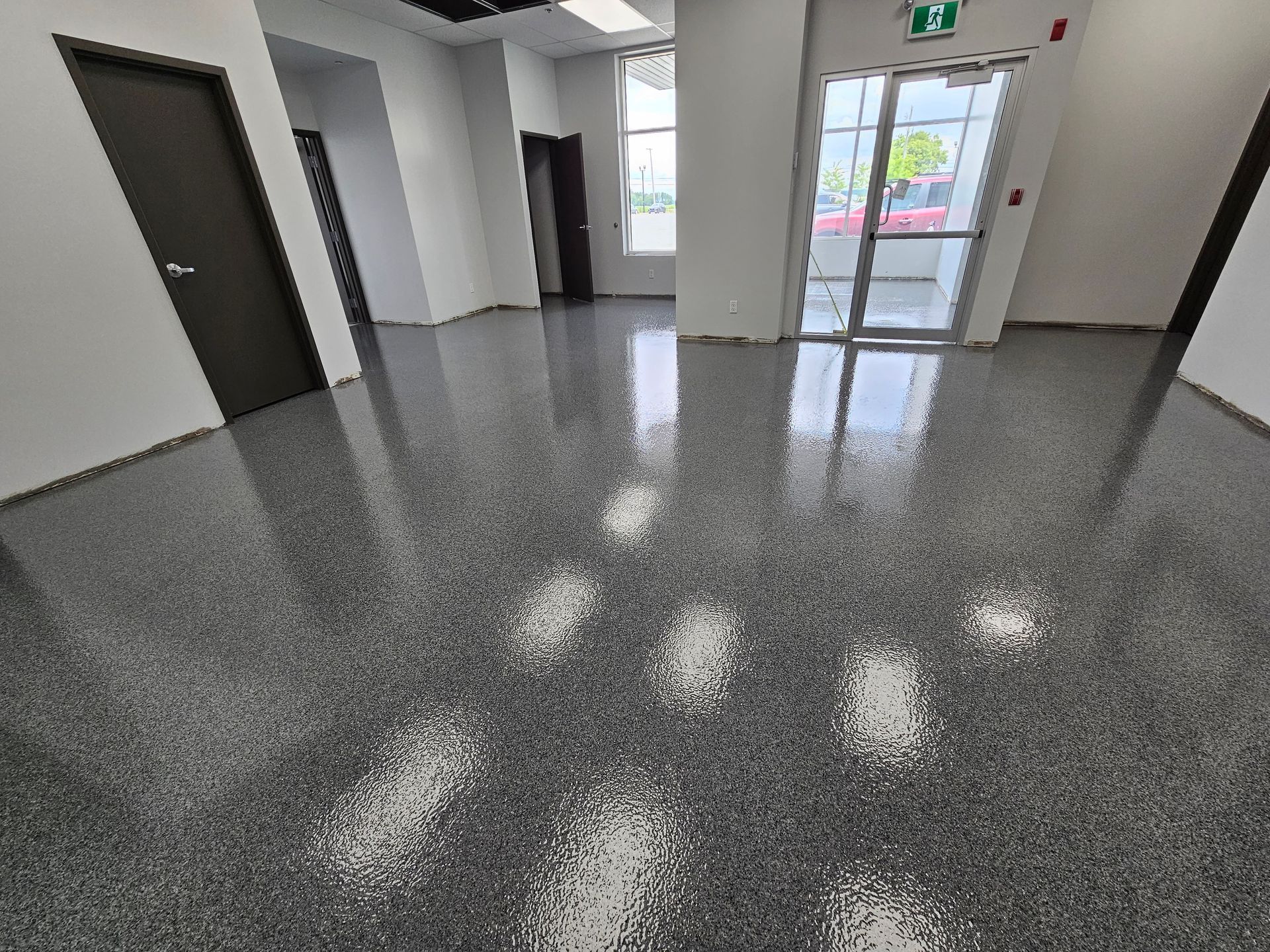 Revêtement de sol époxy gris moucheté dans une pièce vide avec la lumière se reflétant sur la surface brillante.