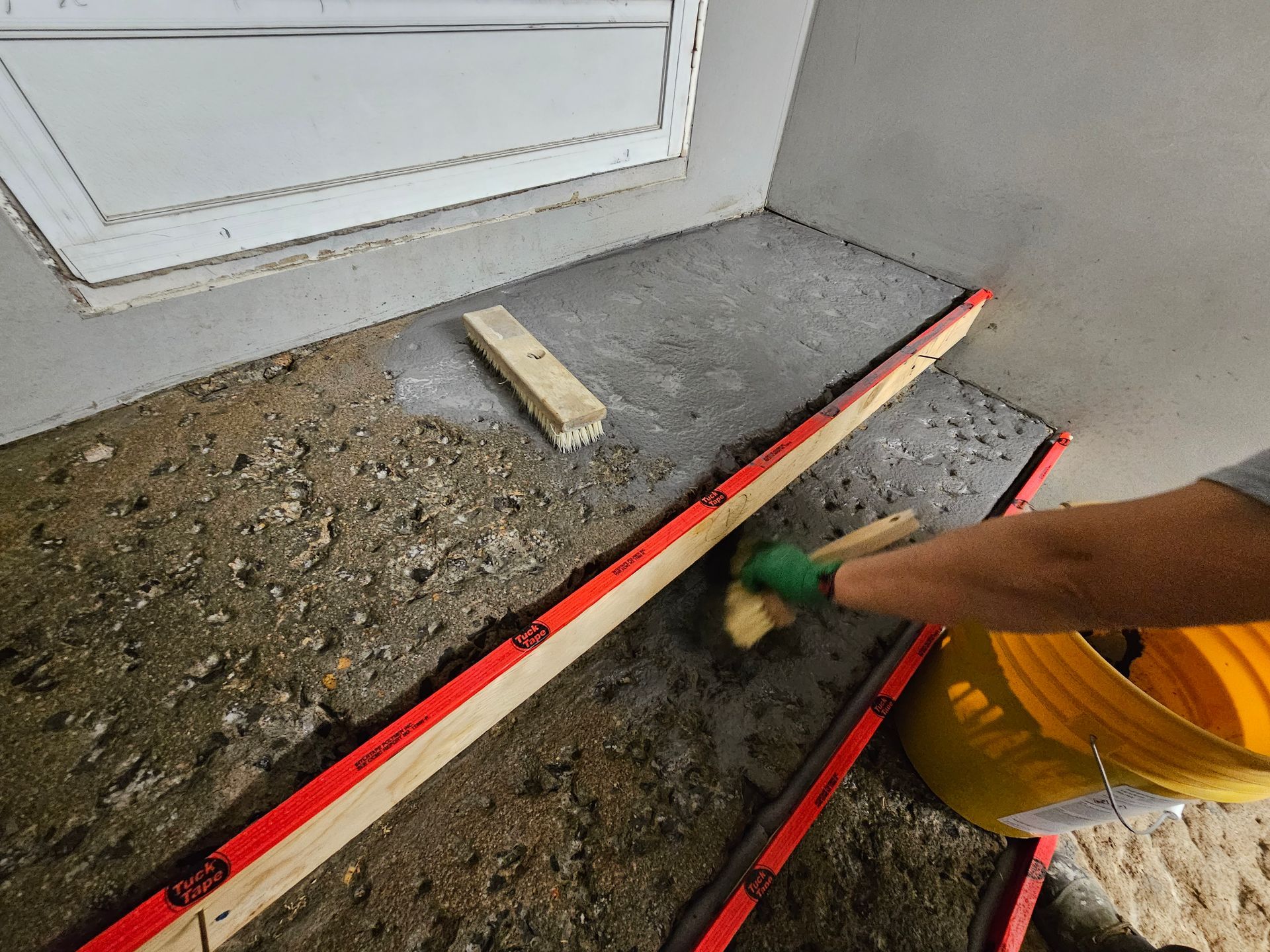 Intérieur d'une pièce rustique avec poutres apparentes, cheminée en briques et sol en béton.
