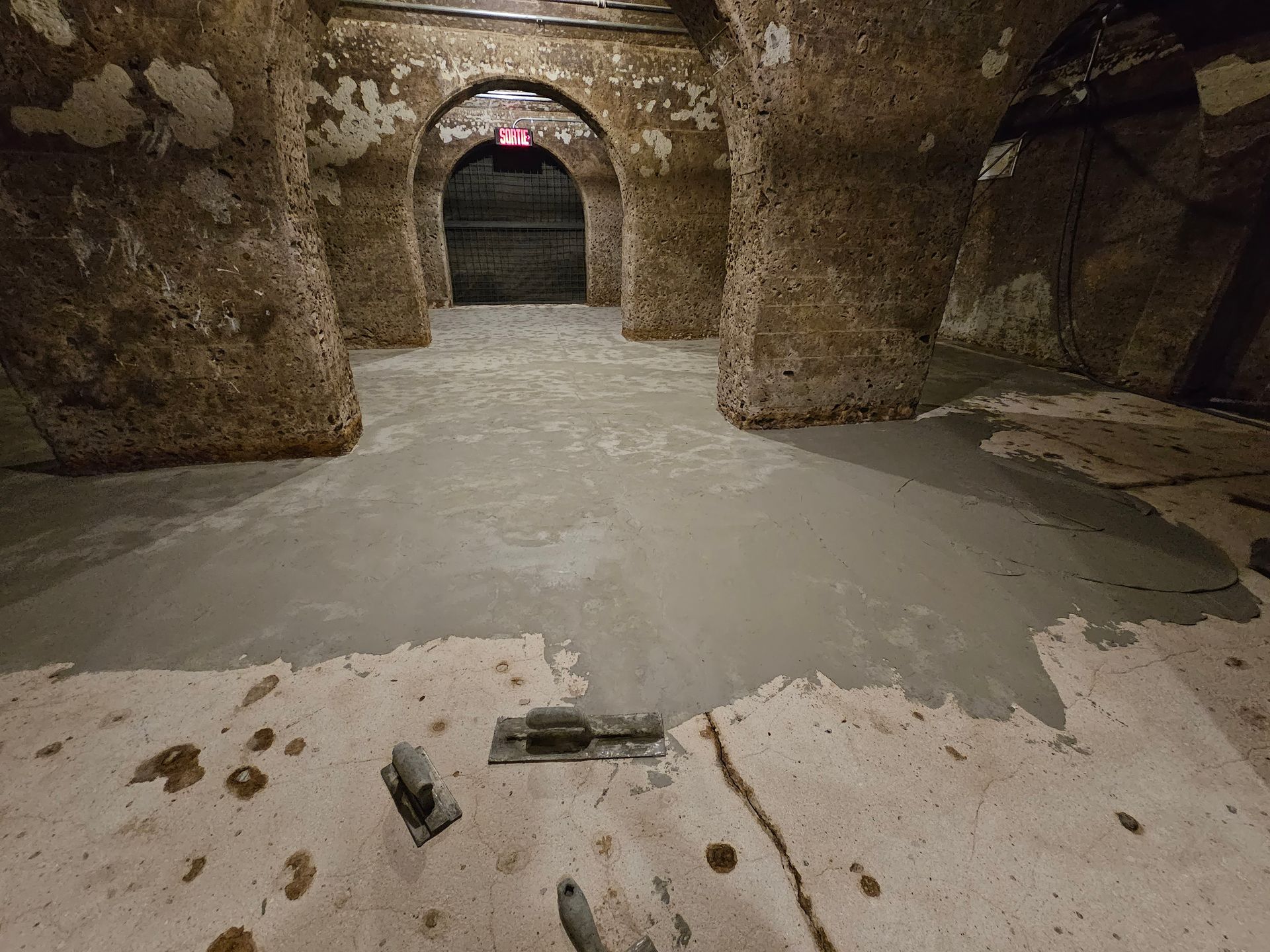 Intérieur spacieux avec cheminée en brique, poutres en bois et sol en béton.