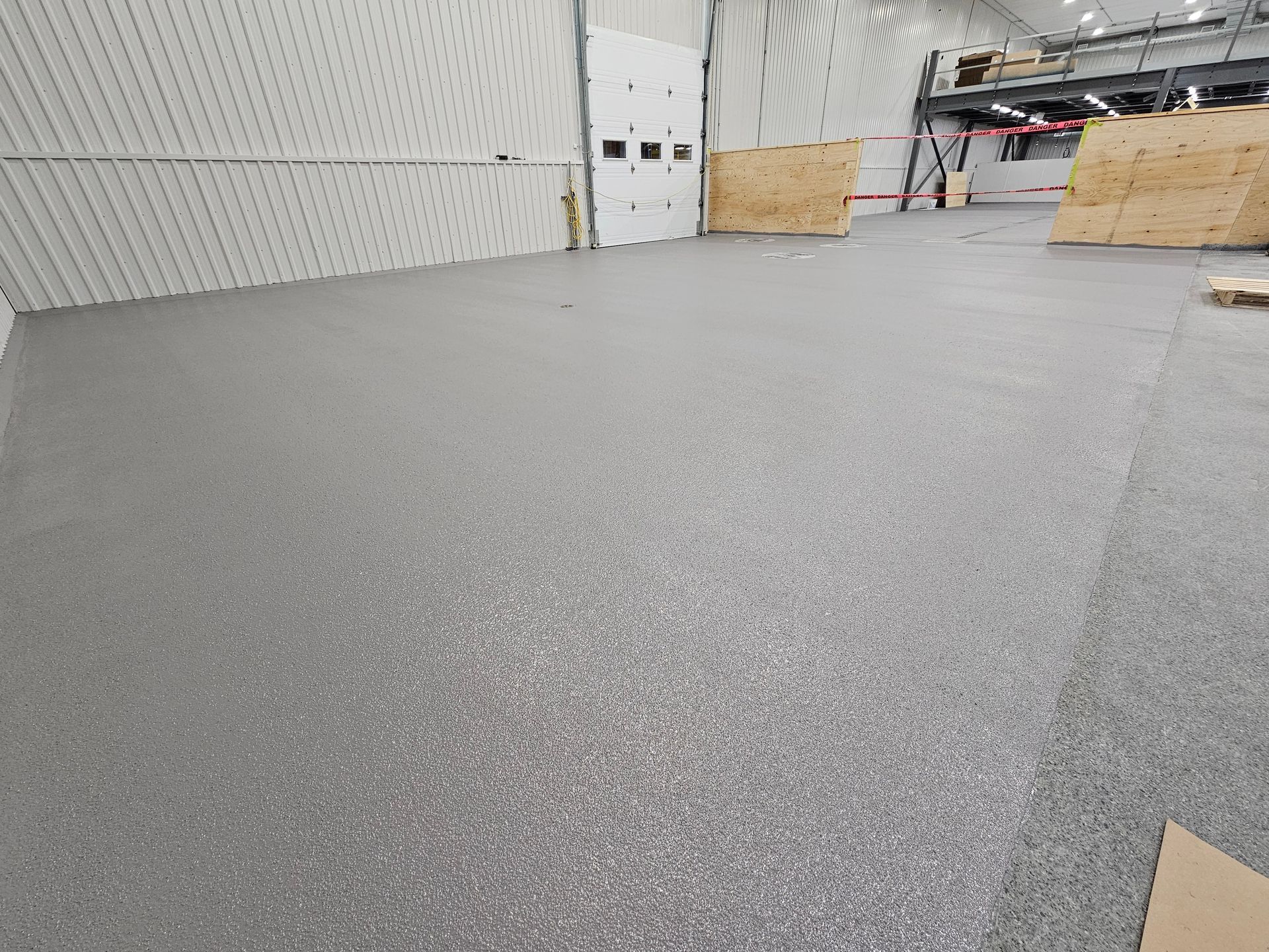 Sol époxy métallique aux tons gris, bronze et argent tourbillonnants ; porte et mur en bois en arrière-plan.