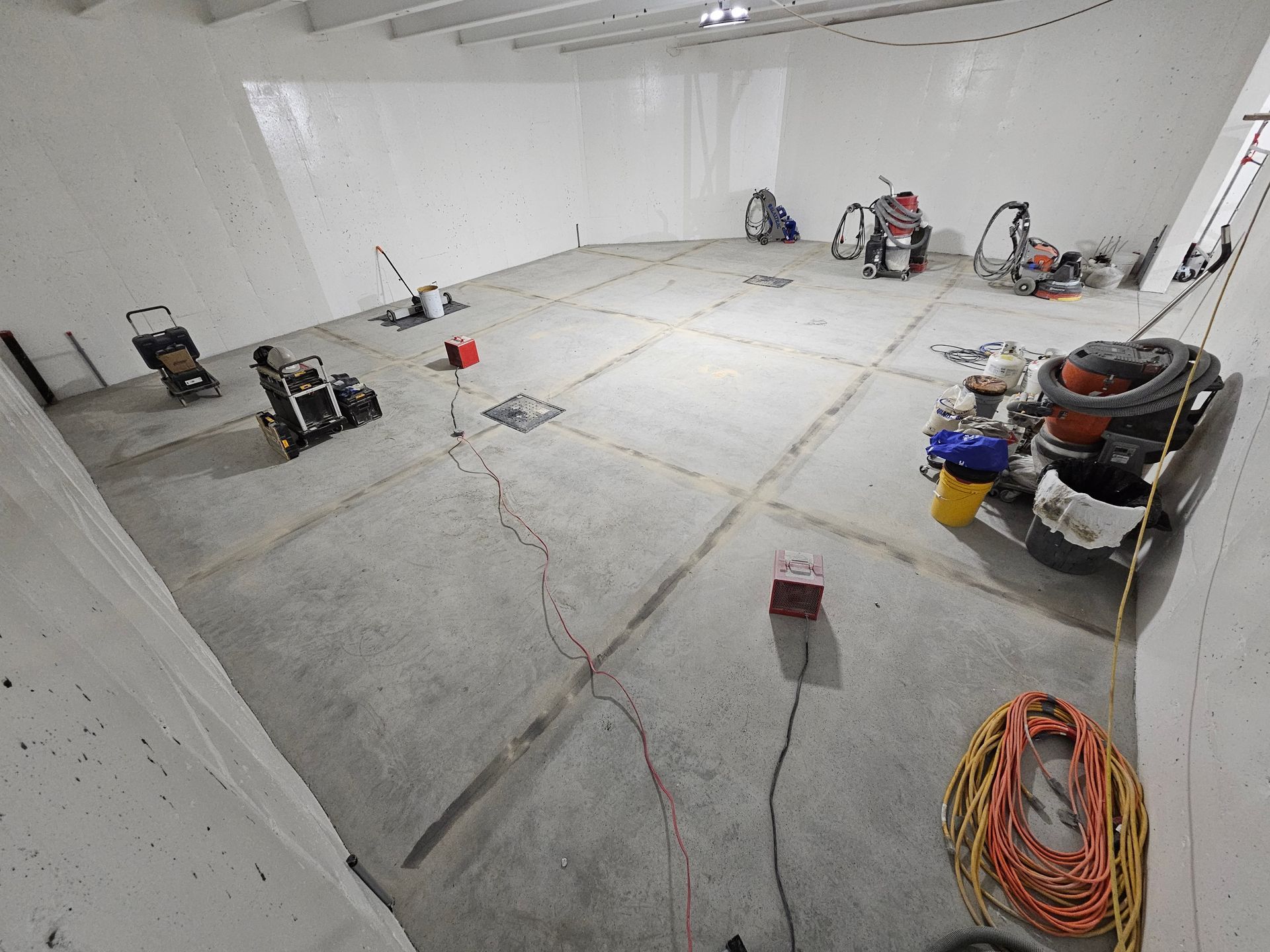 Un sol en béton dans une pièce avec des outils et des fournitures de construction éparpillés.