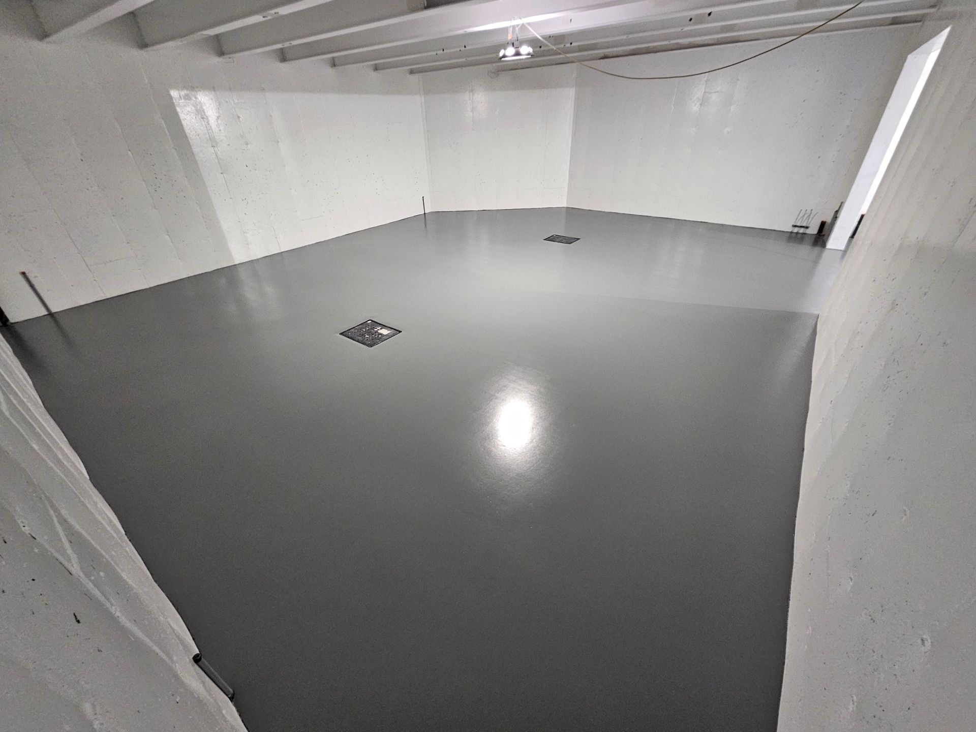 Sol époxy métallisé brillant aux tons marron et argent. Une porte en bois et des tuyaux sont visibles.