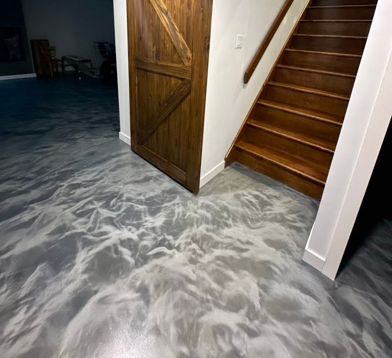 Plancher époxy gris métallisé et blanc avec porte et escalier en bois.