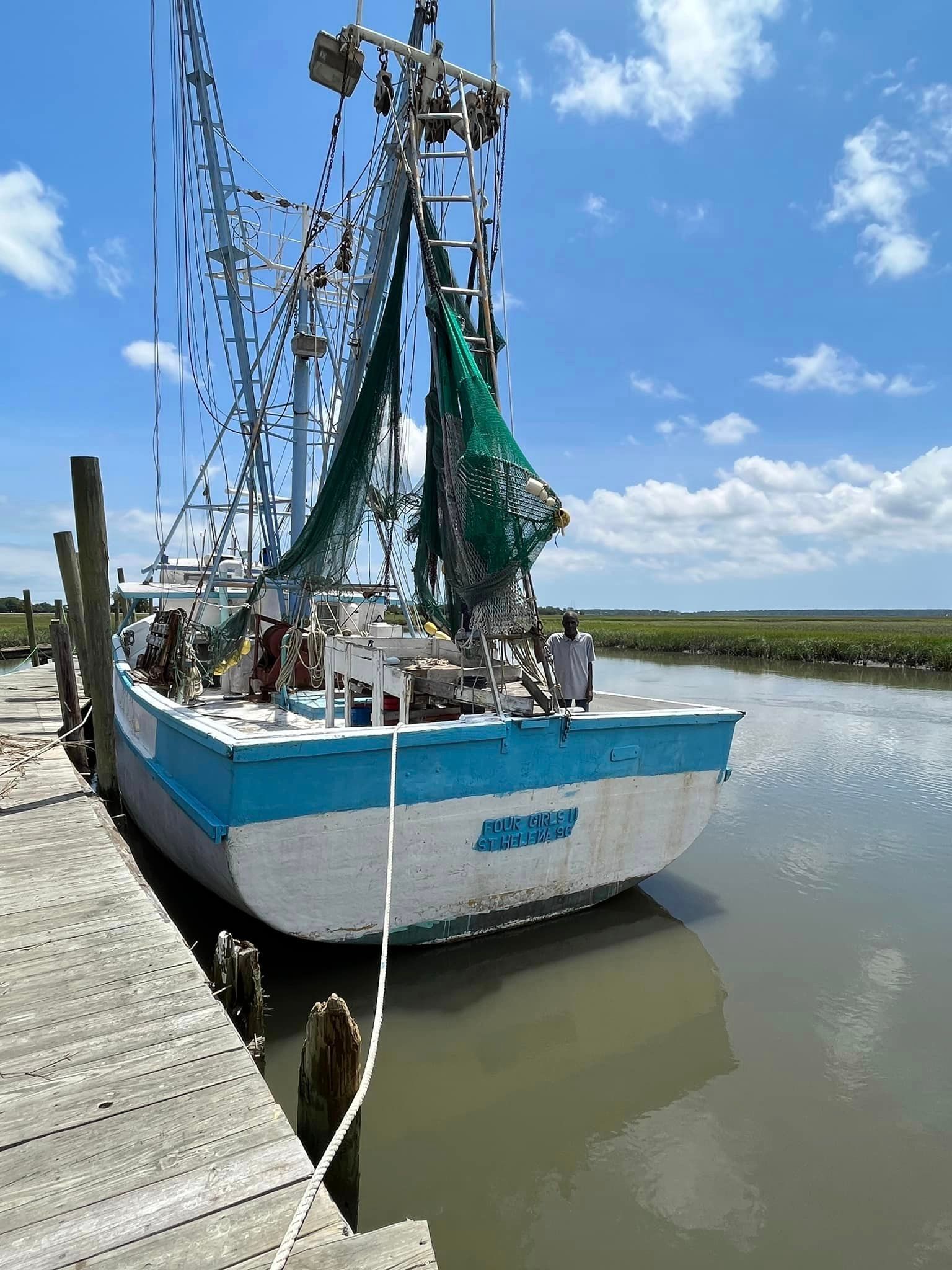 A blue and white boat is tied to a dock in the water.