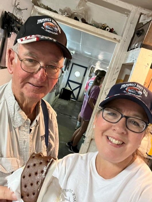 A man and a woman are posing for a picture while holding an ice cream cone.