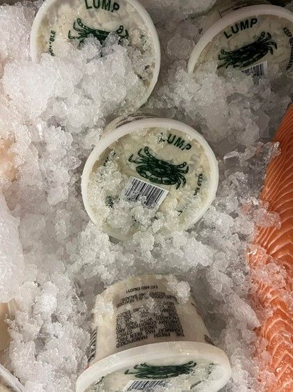 A close up of a container of lump crab on ice.