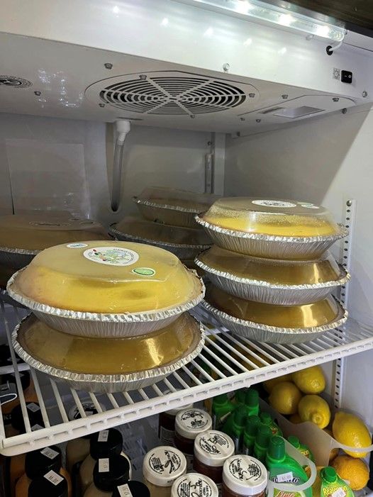 There are many pies stacked on top of each other in a refrigerator.