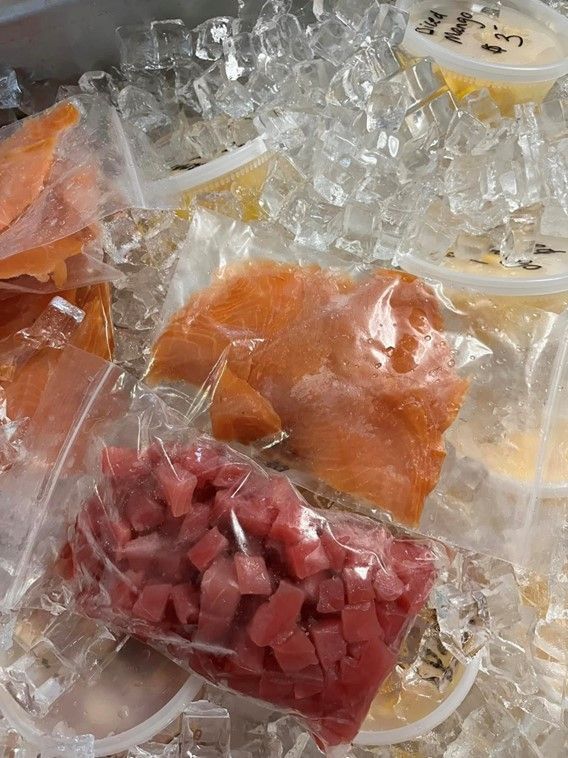 A bunch of plastic bags of food are sitting on top of ice.