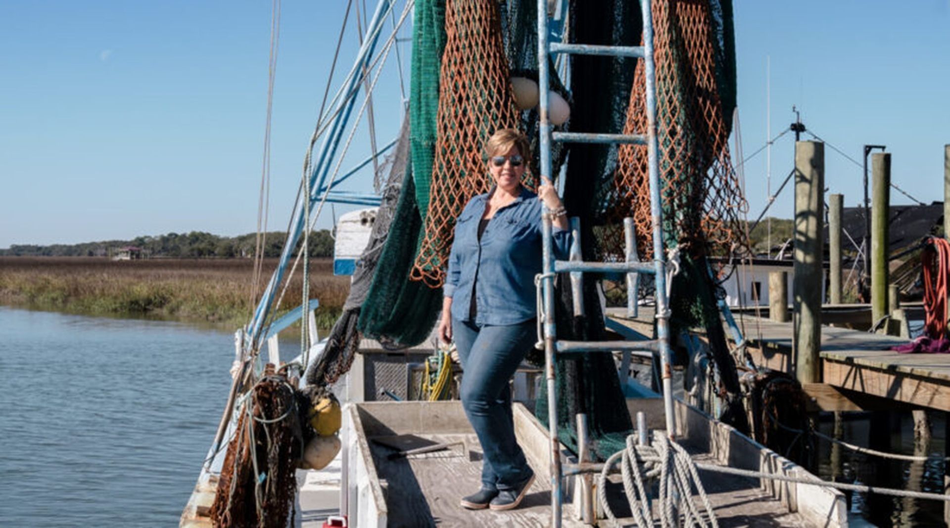 A woman is standing on a boat next to a ladder.