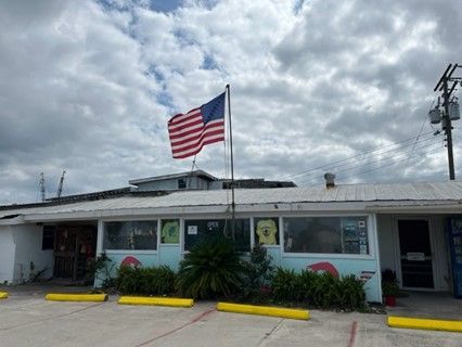 Two american flags are flying in front of a building.