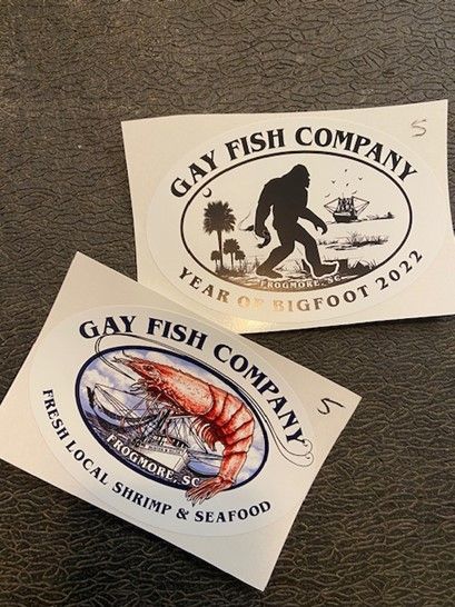 Two stickers from the gay fish company are sitting on a table.