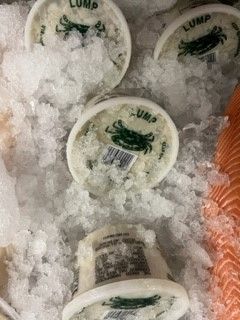 A container of lump crab meat is sitting on top of ice.