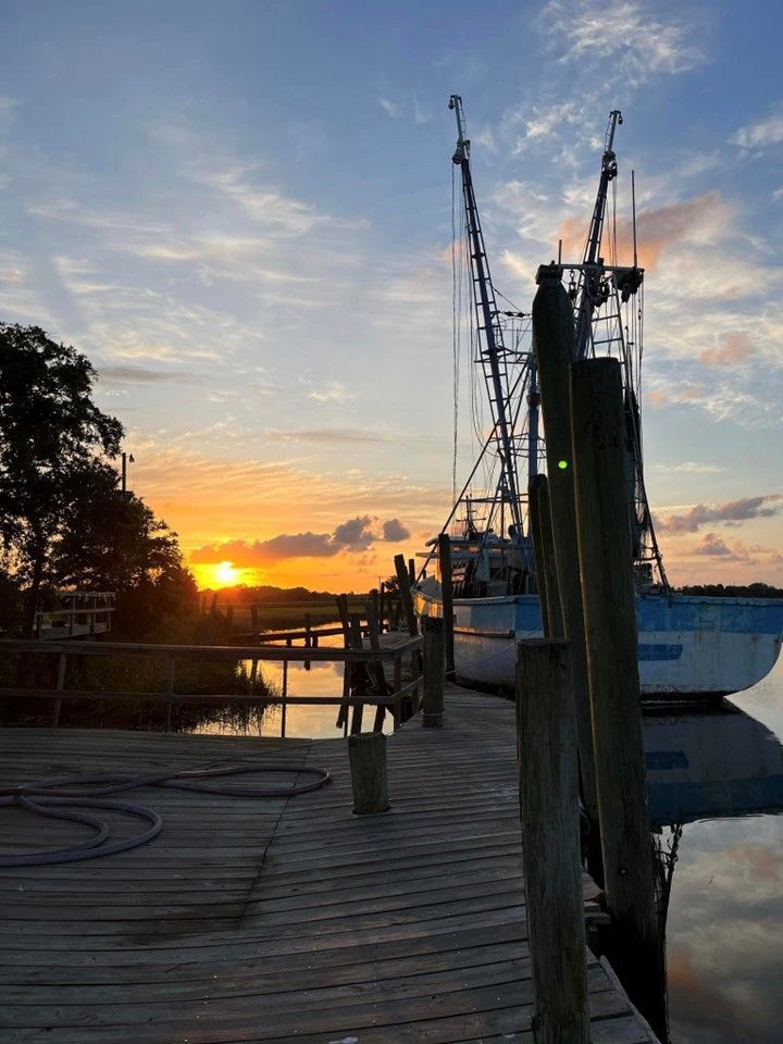 A boat is docked at a dock at sunset