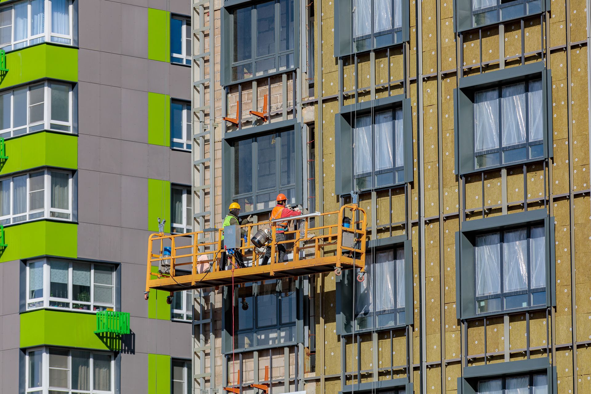 Male builders work on the facade of the building.