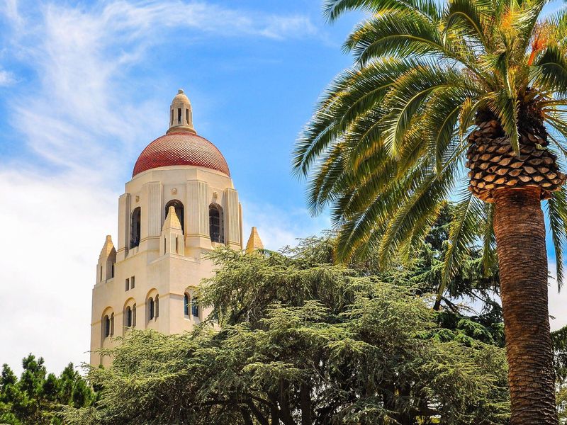 A large building with a dome on top of it is surrounded by palm trees.