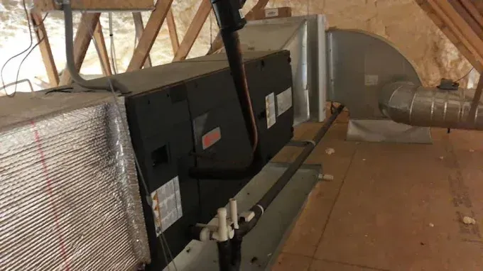 HVAC unit in an attic. Ductwork, piping, and insulation are visible.