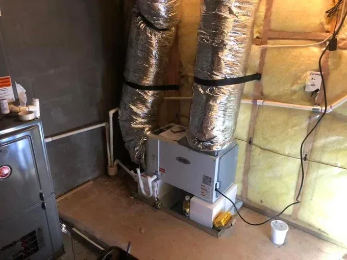 HVAC system with silver ductwork in a basement setting.