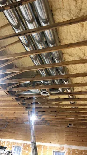 Wooden rafters with metal ductwork, and insulation.