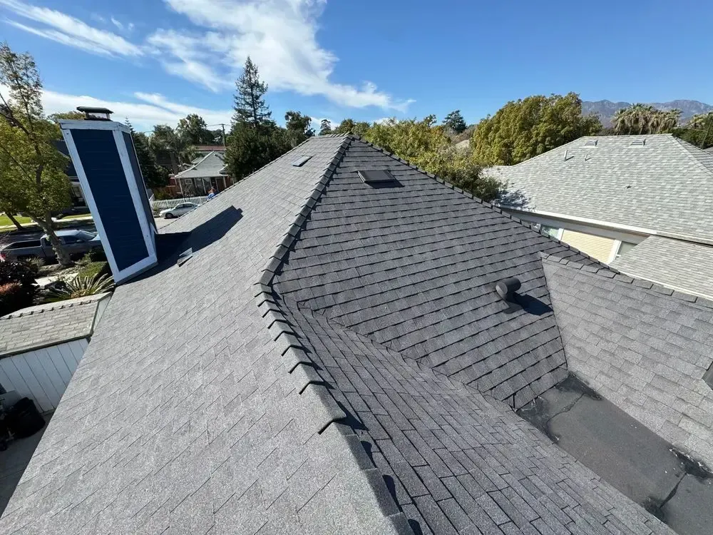 The roof of a house with a chimney and a solar panel on it.