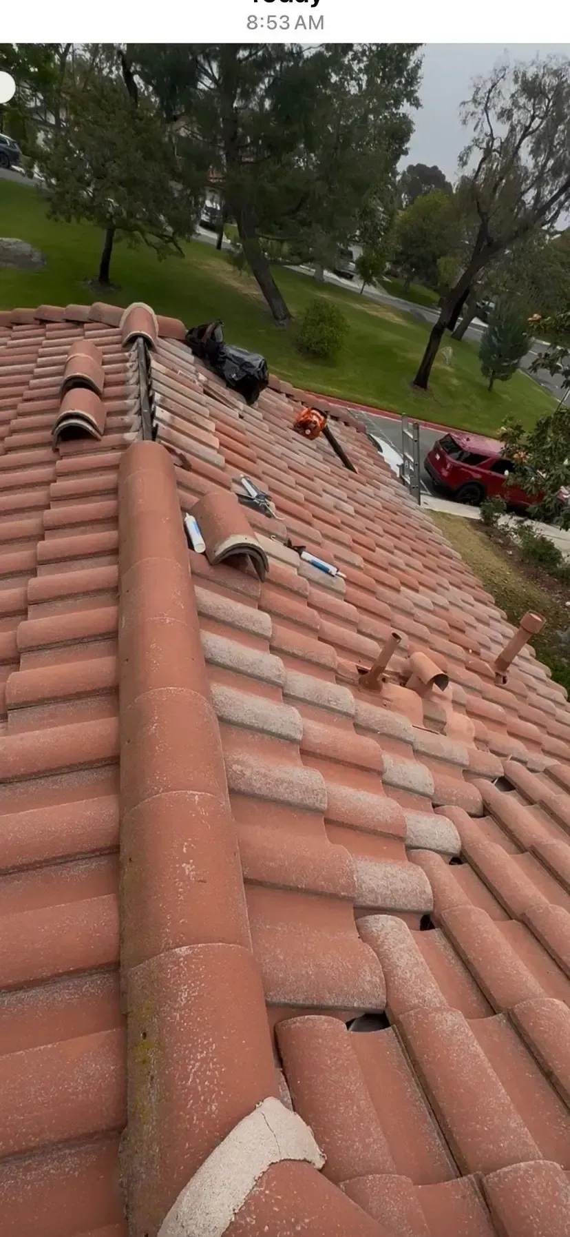 A close up of a tiled roof with a red car parked in the background.