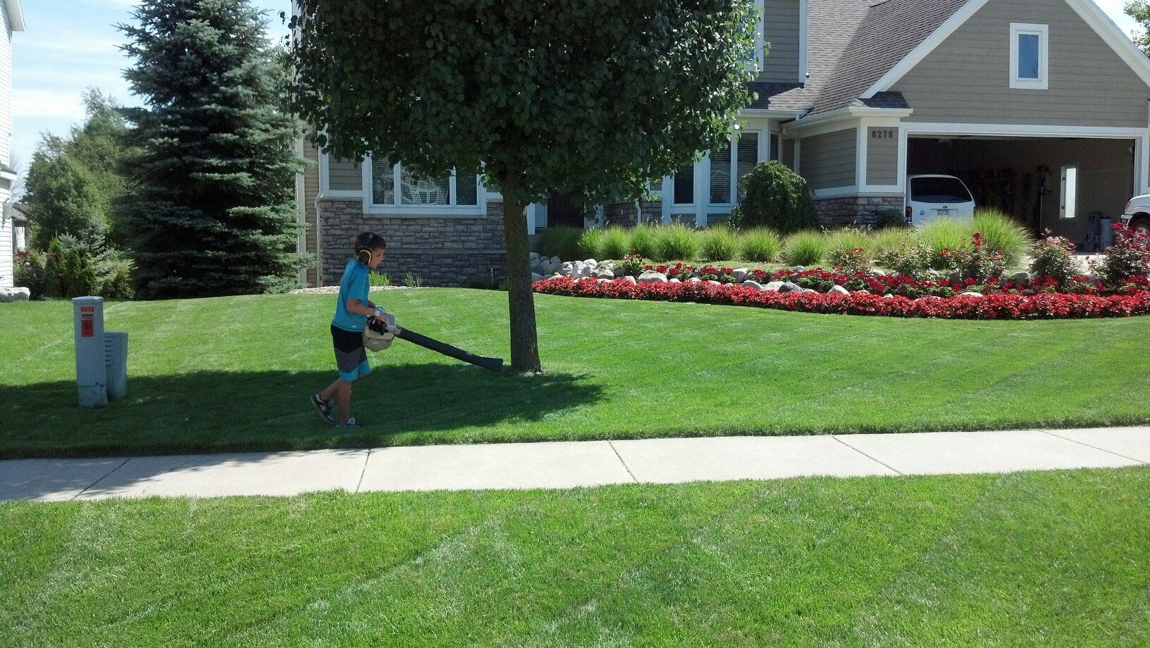 A boy is playing with a bat in front of a house.