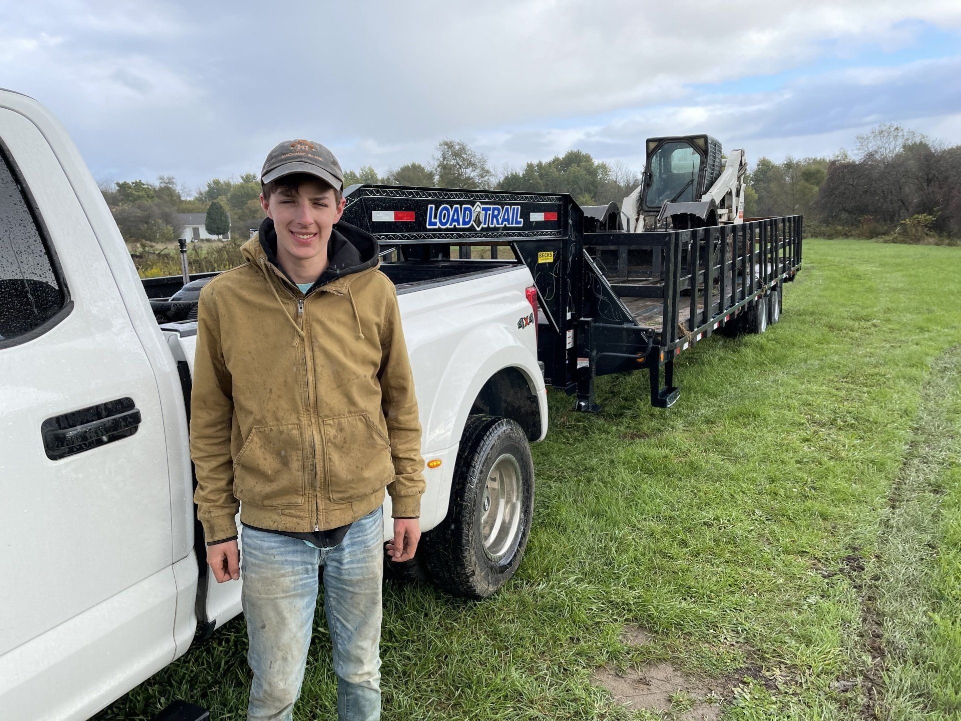 A man is standing next to a truck with a trailer attached to it.