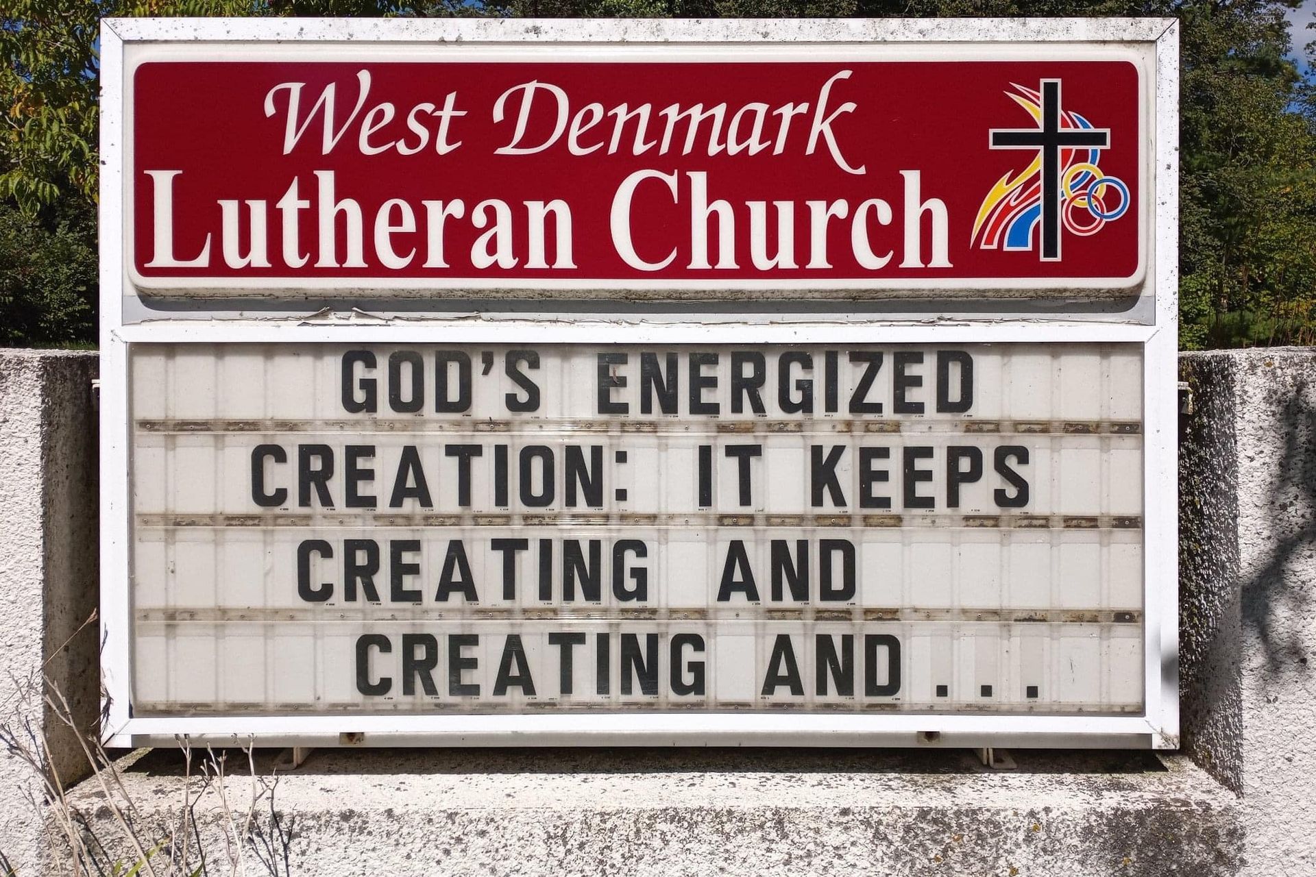 A sign for west denmark lutheran church says god 's energized creation it keeps creating and creating and