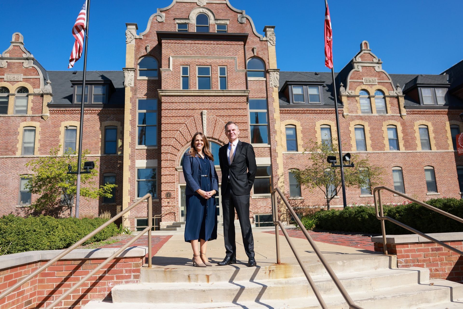A man and a woman are standing in front of a large brick building.