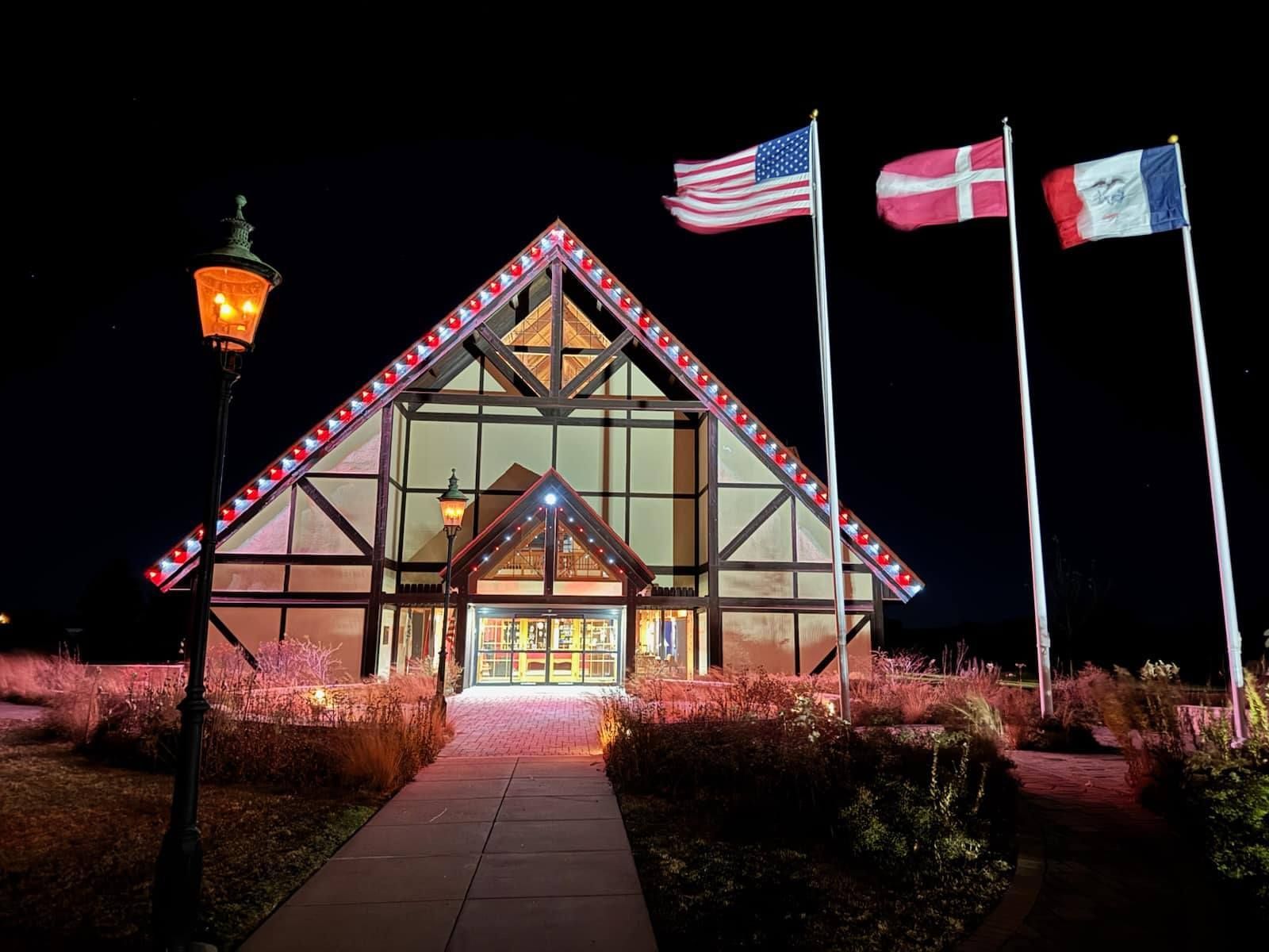 Three flags are flying in front of a building at night