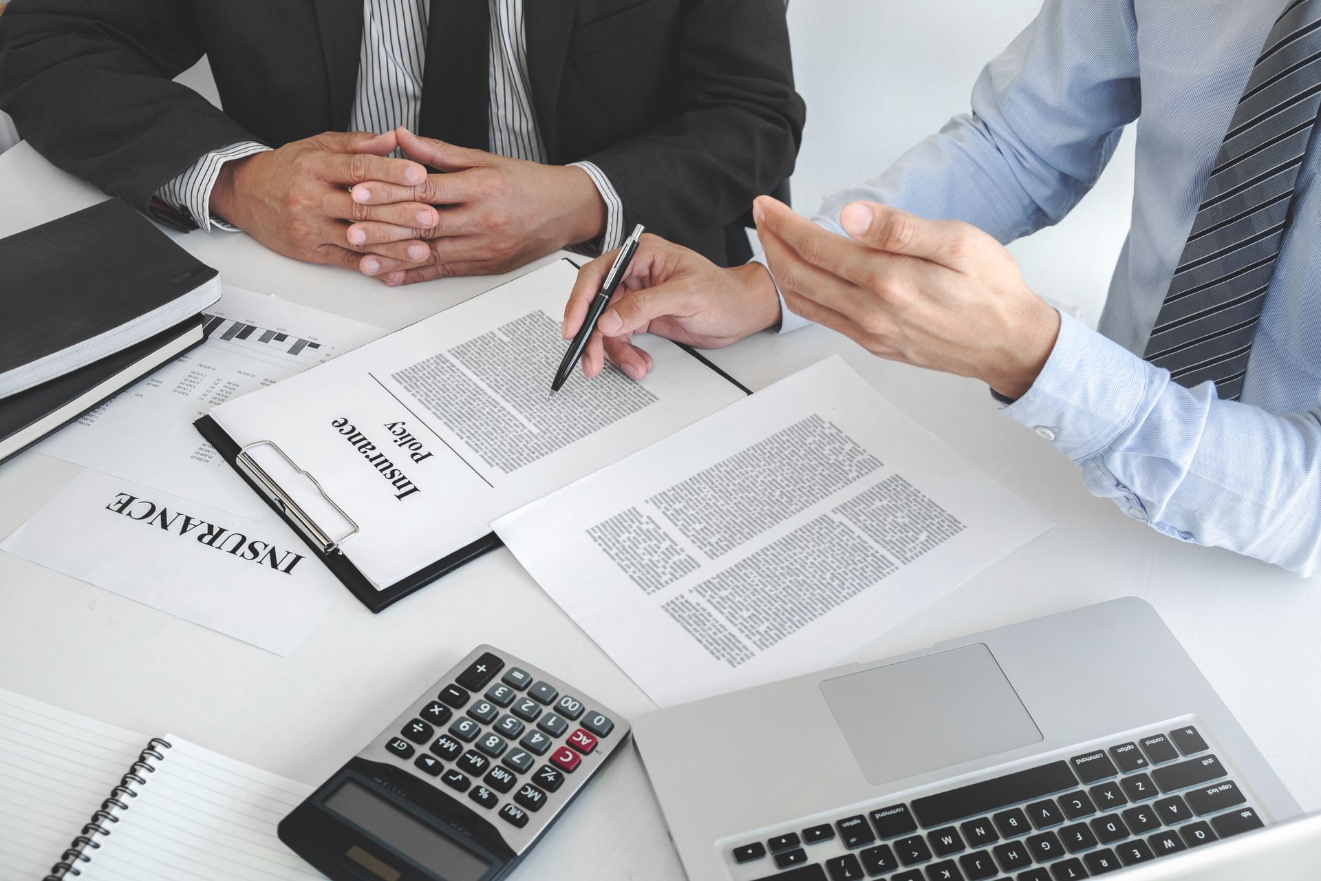 An insurance agent discussing policy documents with a client at a desk