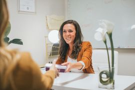 A woman is handing a lab test to a client in an office