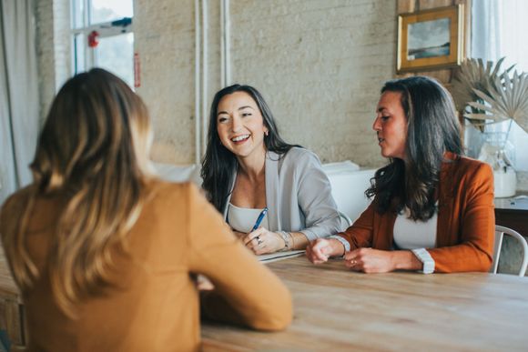 Noel laughing at table with coworkers
