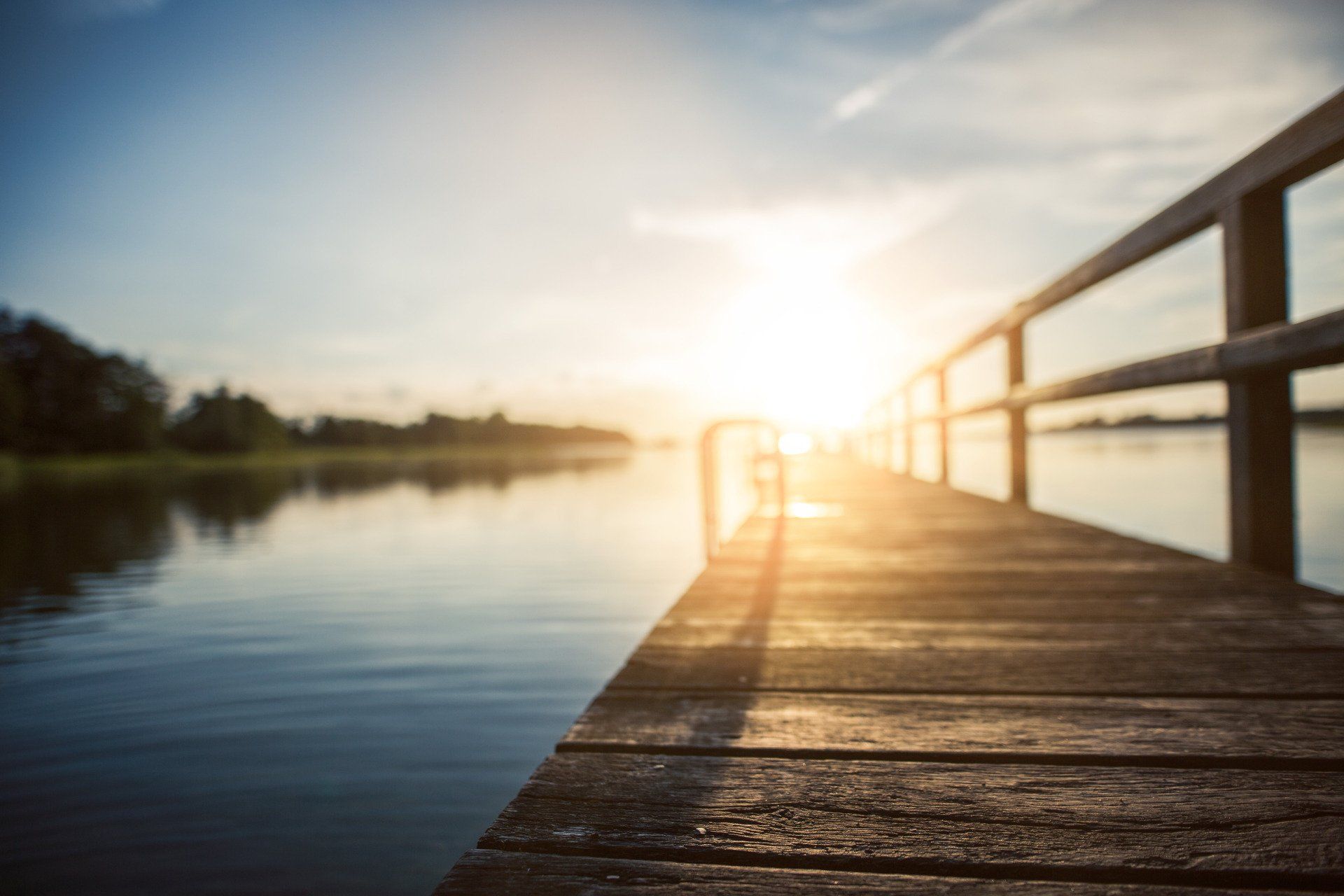A wooden pier overlooking a lake at sunset.