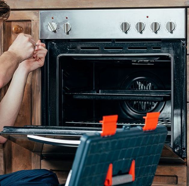 Worker Repairing Kitchen Oven — Coral Springs, FL — Central Appliance Repair LLC