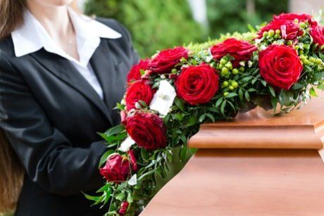 rose rosse su un cofano funebre