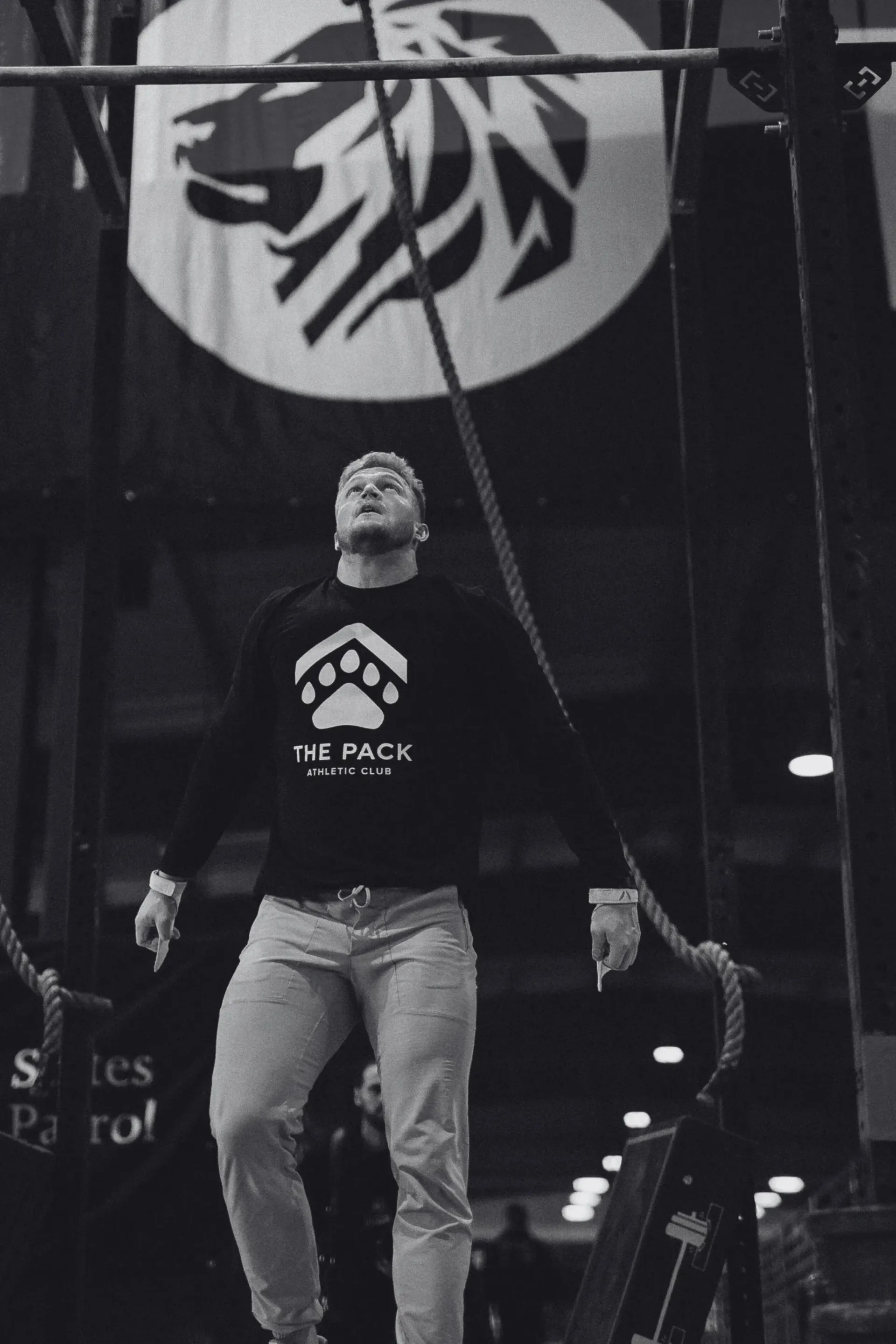 Two men in a gym. One sits, looking up, the other high-fives. Weights in the background.