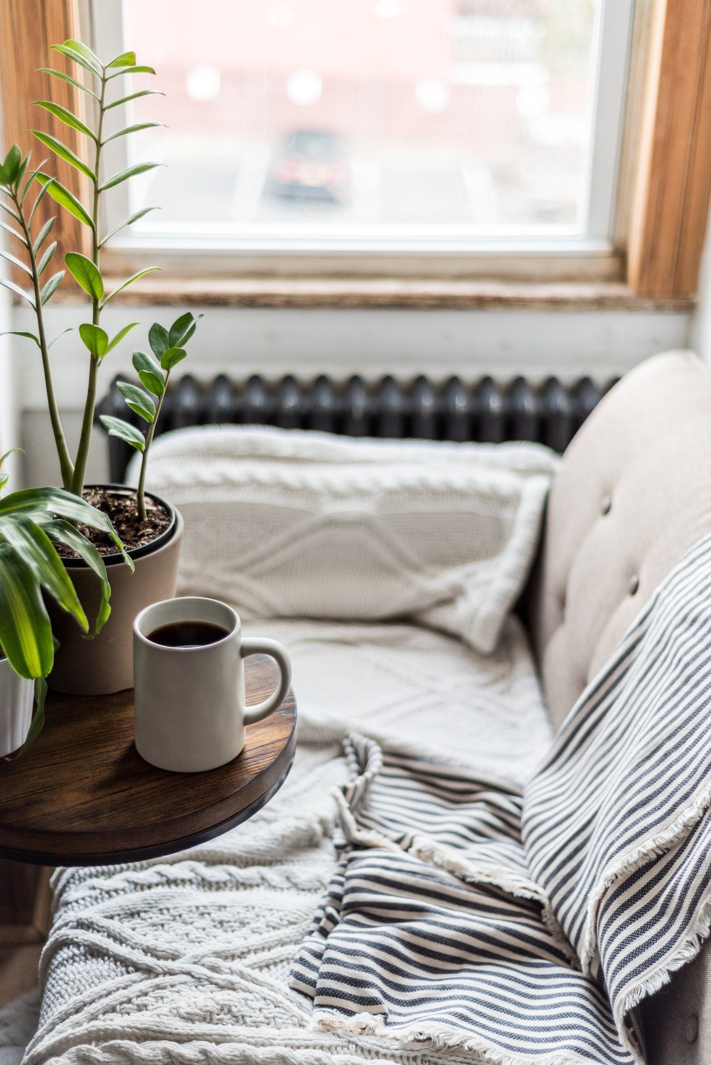 A couch with a blanket and a cup of coffee on it.