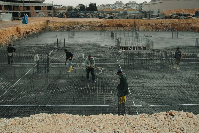 Construction workers applying concrete to a buildings foundation