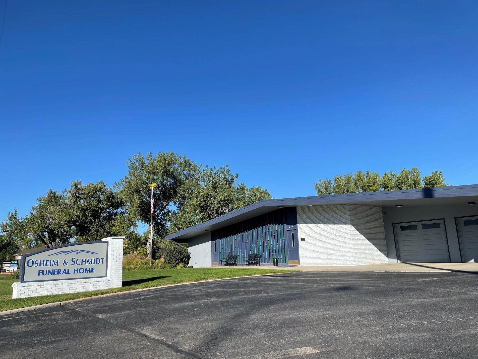 Sign for Presbyterian Church, blue and gray building under a bright blue sky.