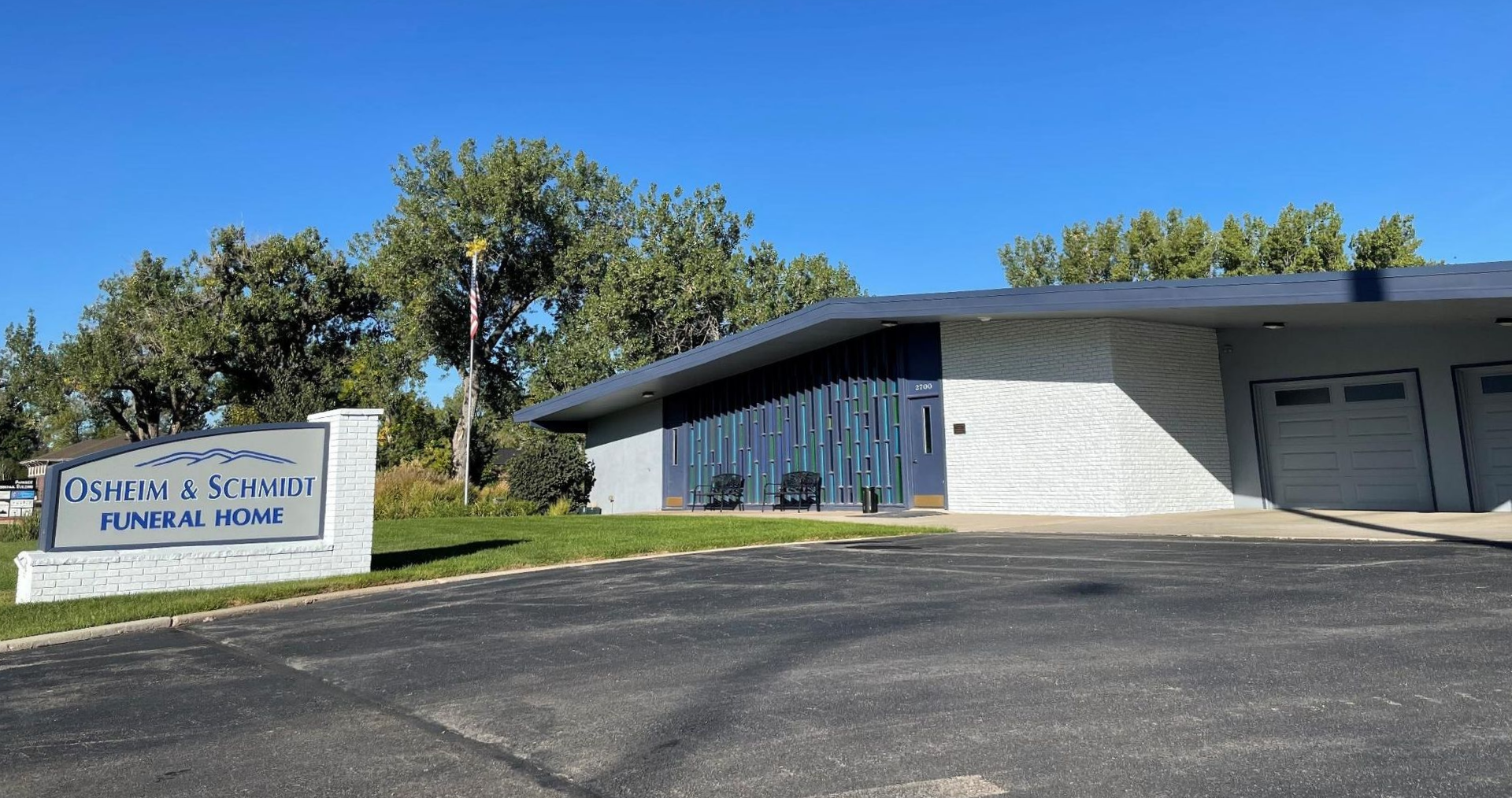 Sign for "Eckert & Schmidt Funeral Home" in front of a modern, single-story building; sunny day.