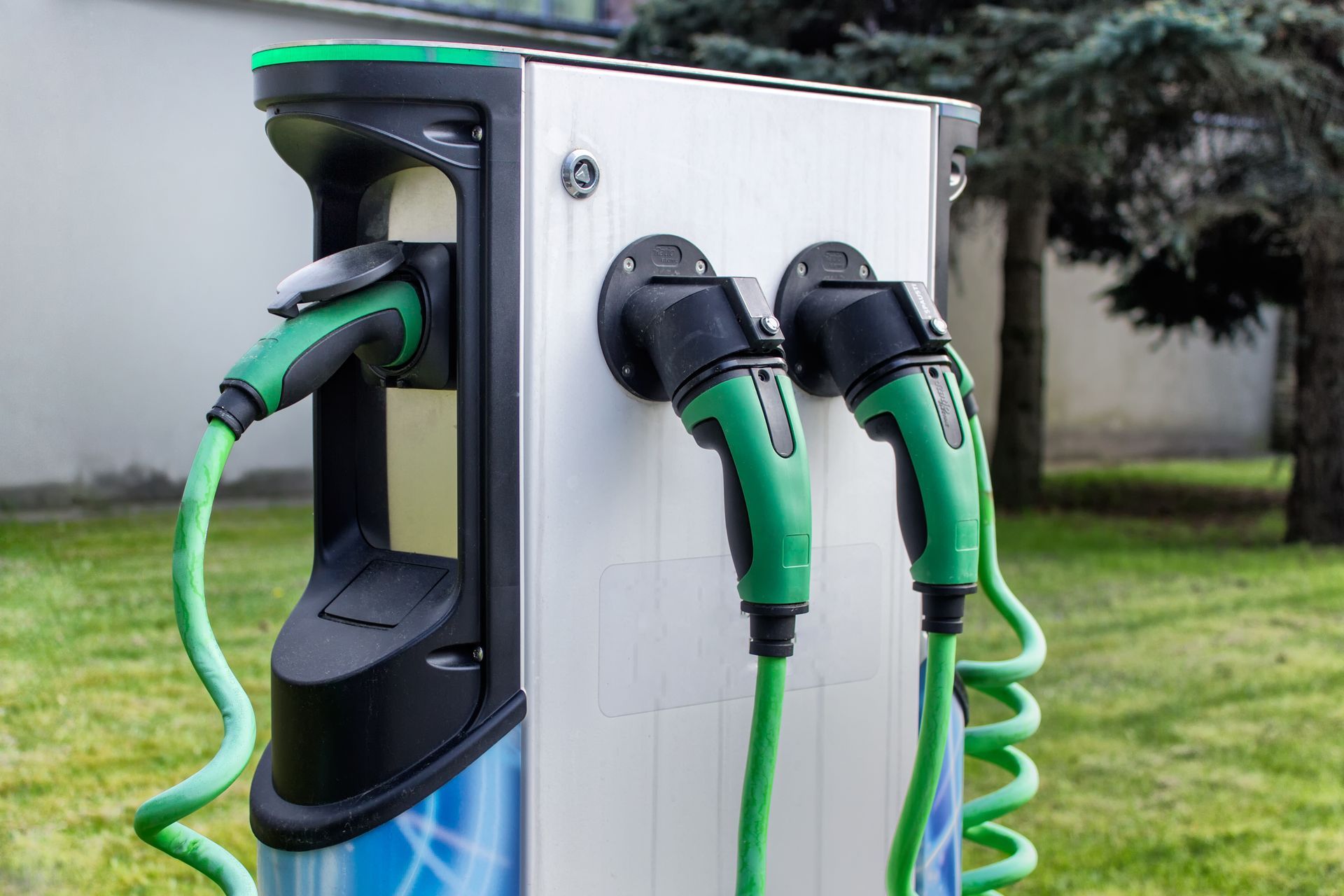 Electric vehicle charging station with charging cables plugged into multiple ports outdoors.