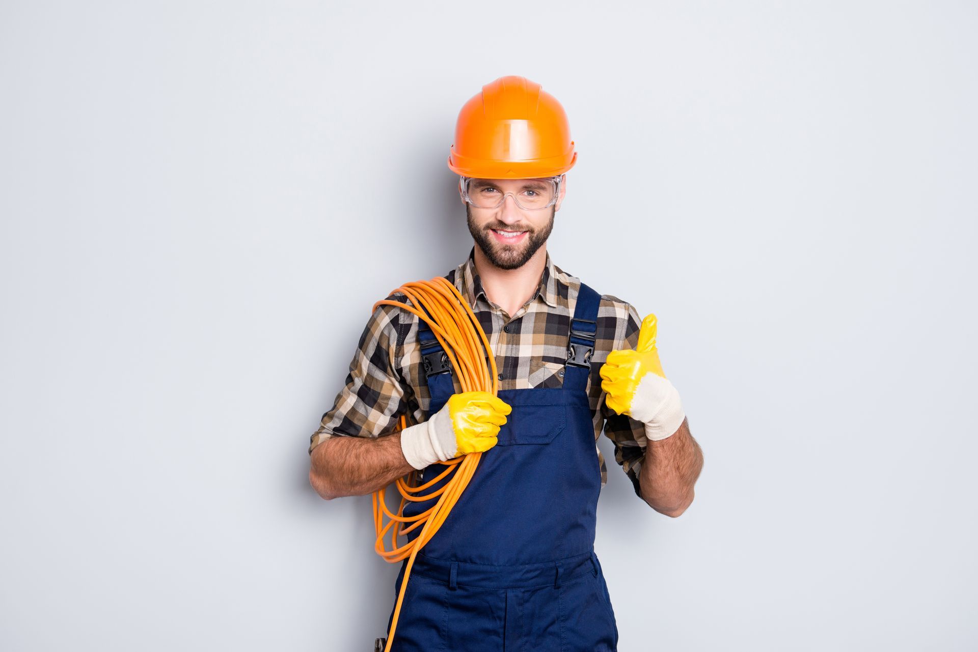 Construction worker in hard hat holding a coiled cable and giving a thumbs up.