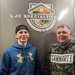 Two men standing in front of a sign that says ljc specialties