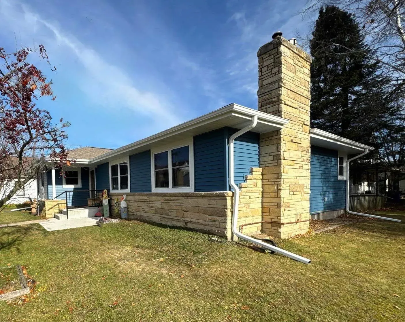 A single-story blue house with stone siding and a stone chimney.