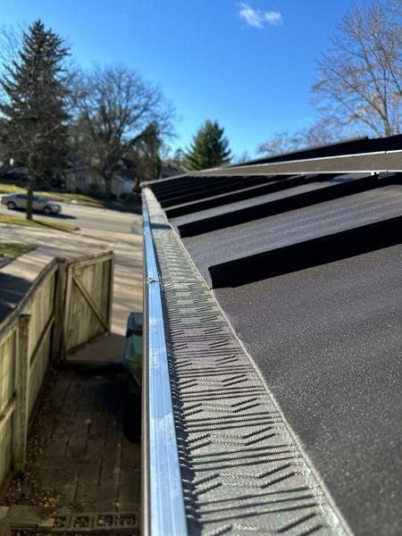 A close-up view of a metal roof edge with a patterned gutter guard.